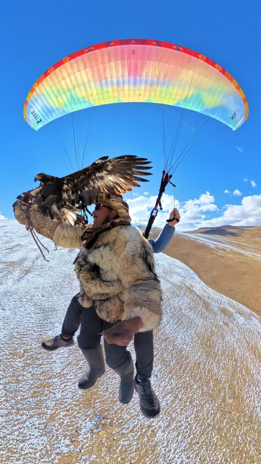 Paraglider soaring over golden Gobi Desert sand dunes